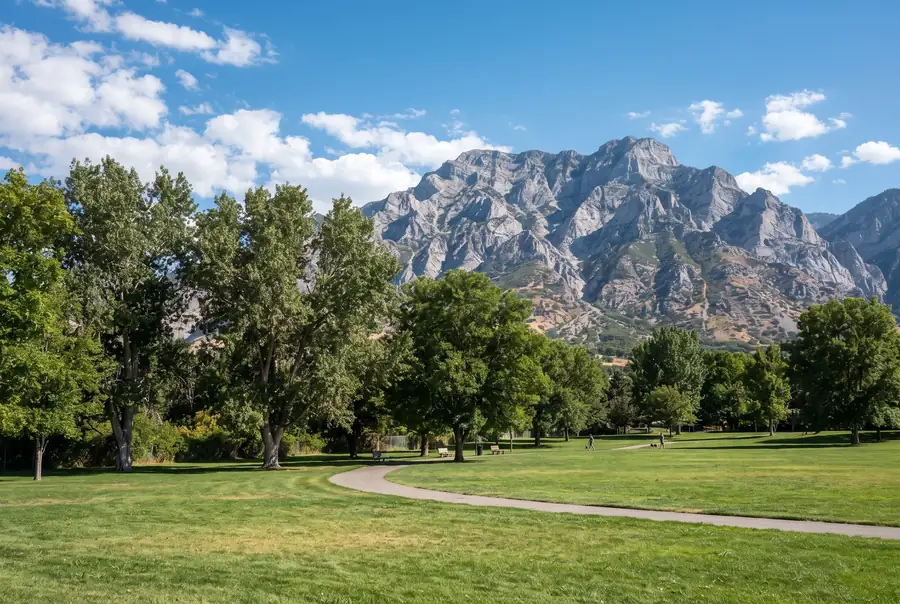 Grassy park with tall cottonwoods below Mount Olympus in Holladay, Utah